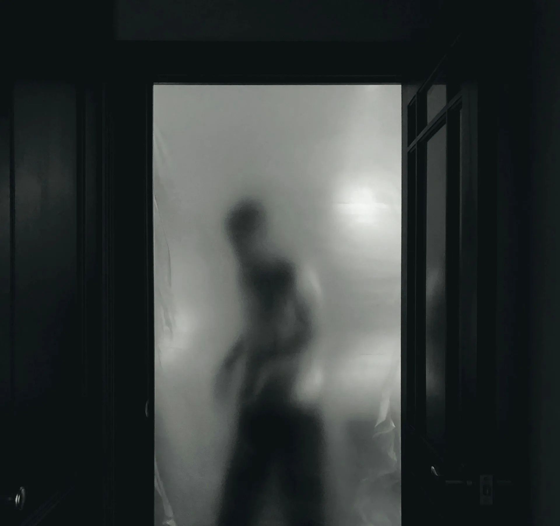 Silhouette behind frosted glass door