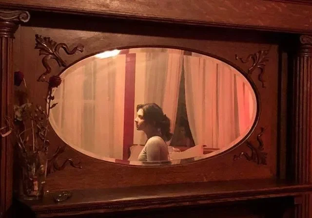 Mirror reflecting woman in dim room