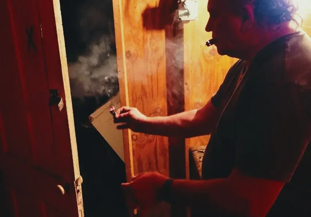 Man exhaling smoke in dark room