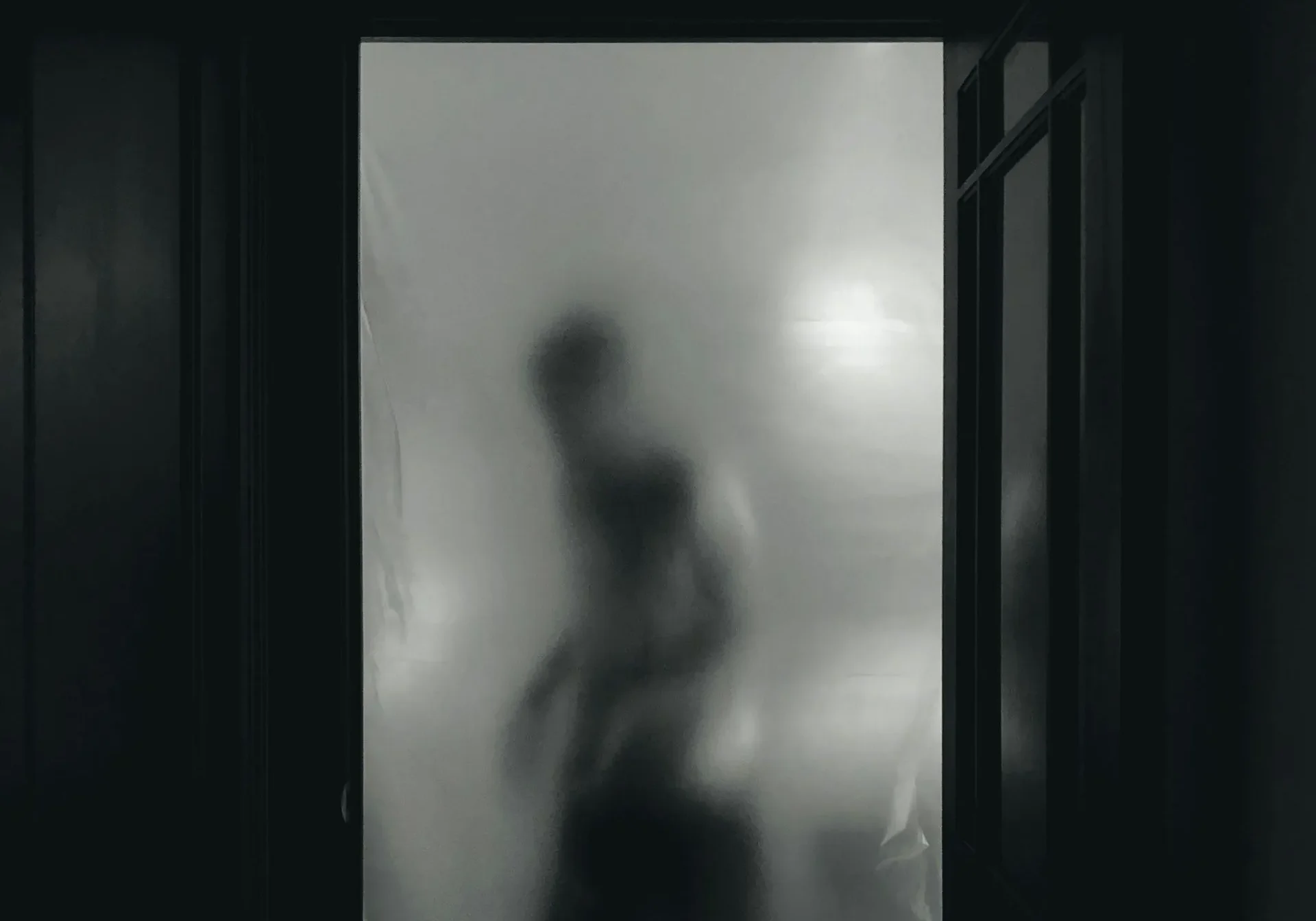 Silhouette behind frosted glass door
